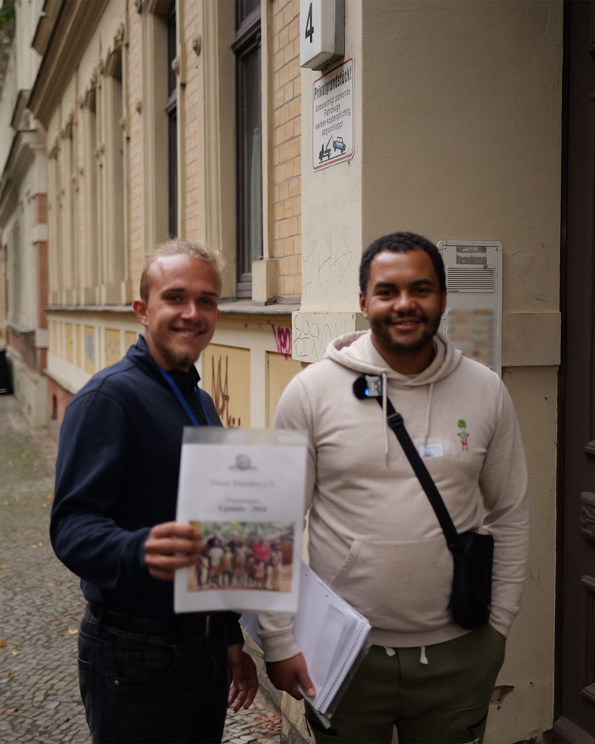 Two members of the association with information material in front of a front door